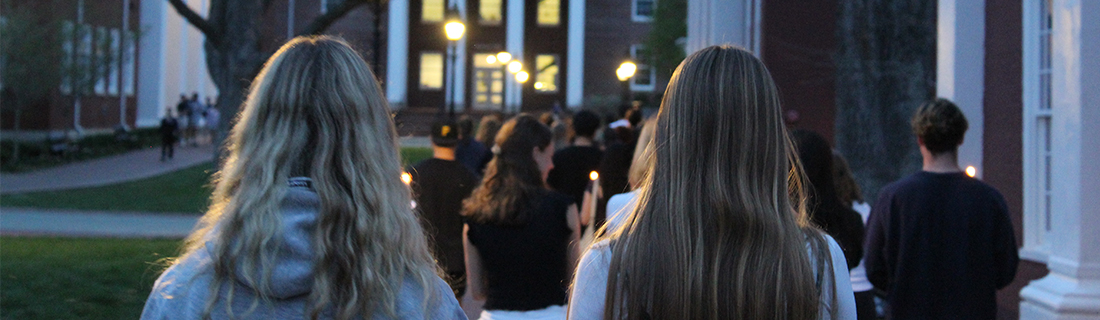 Students walking across campus with candles